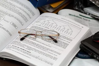 A pair of reading glasses sitting on an open textbook. The book has content on taxes.